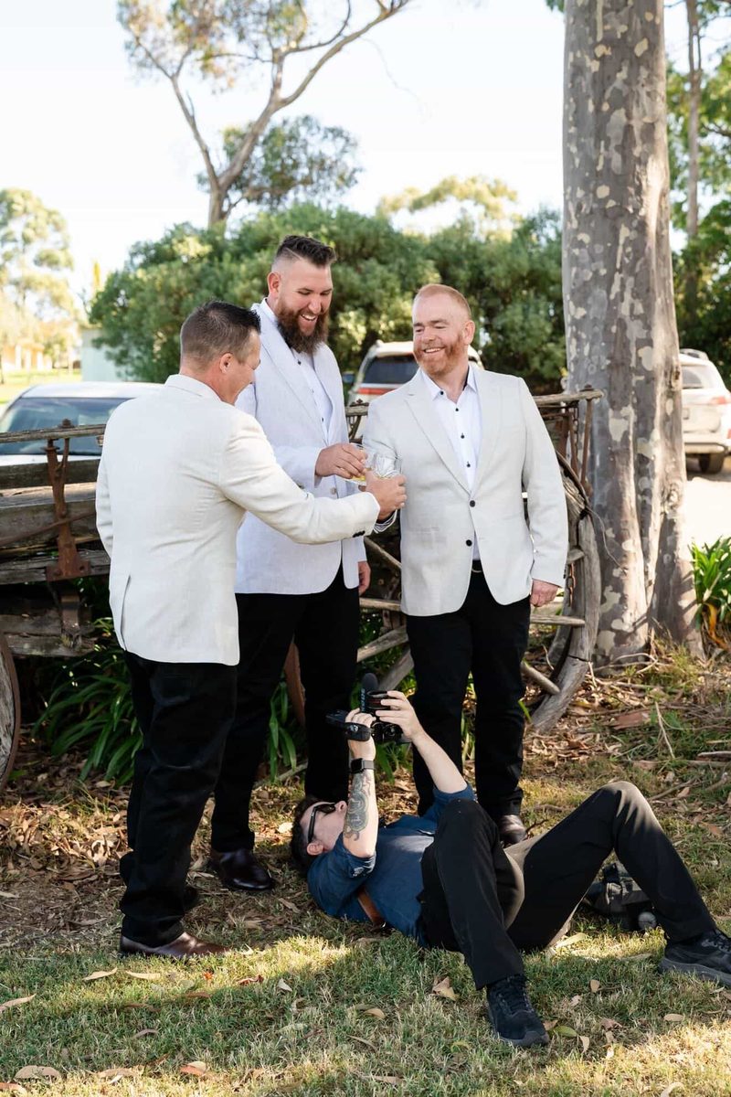 Gareth lying on the grass filming groomsmen toasting