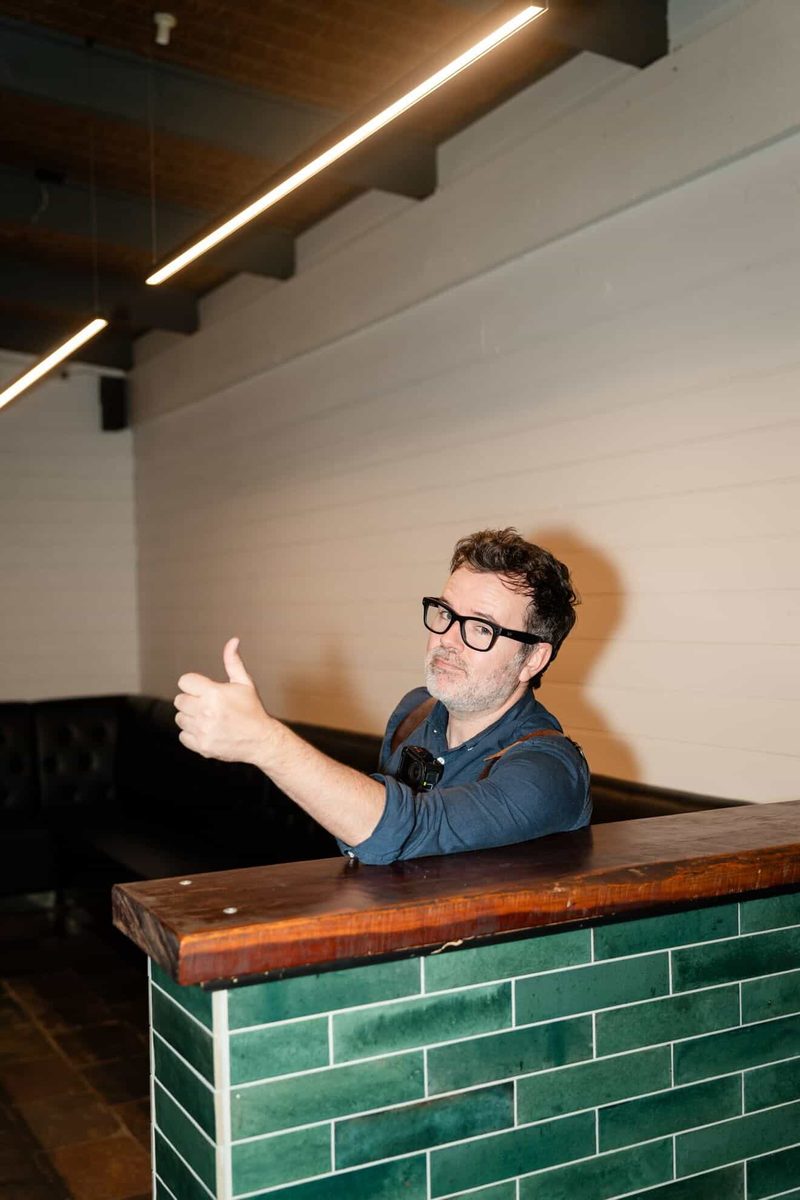 Gareth giving a thumbs up at a green-tiled bar